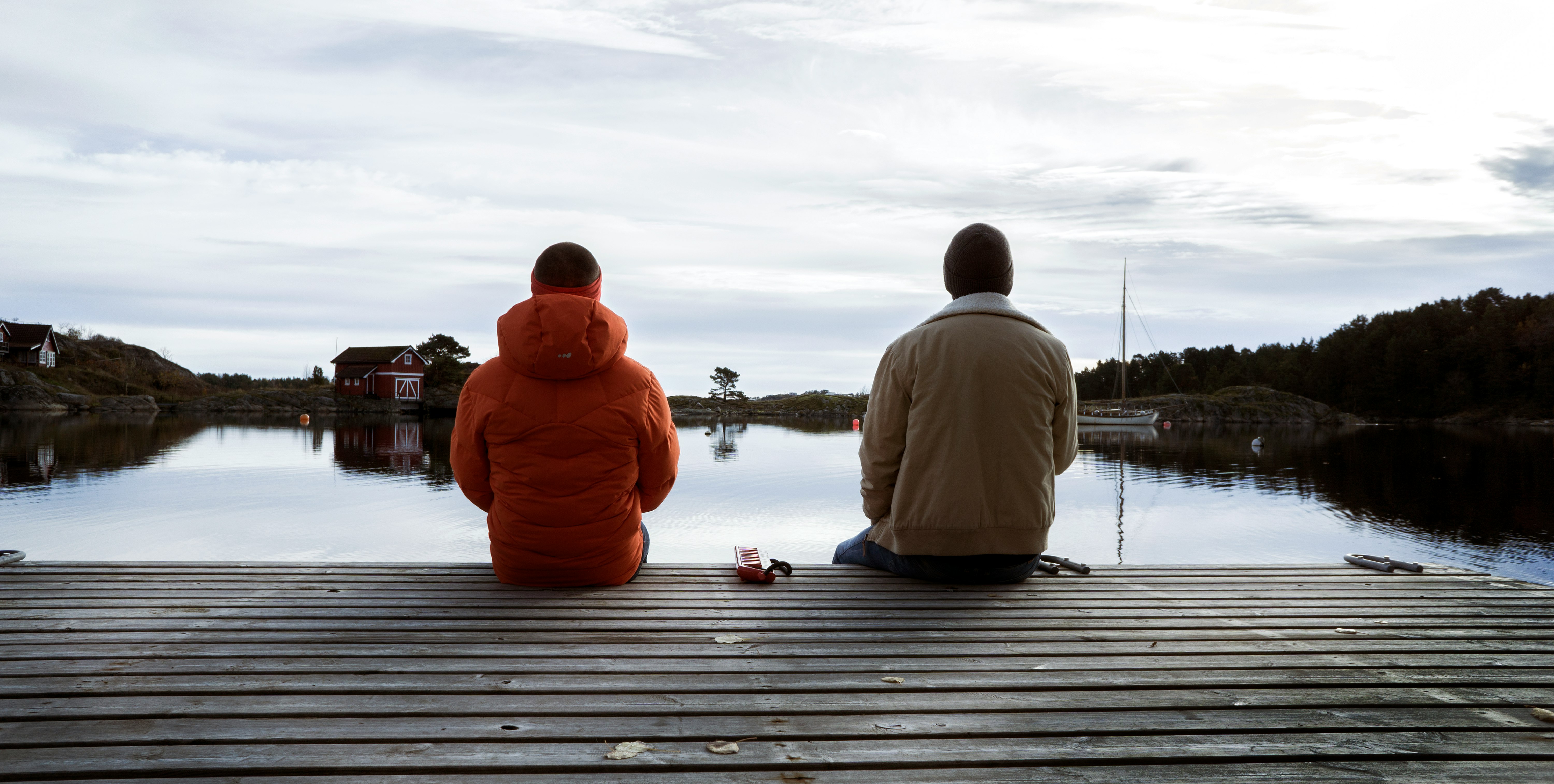 2 men sitting on dock during daytime